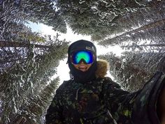 a person with goggles and skis standing in front of some snow covered trees