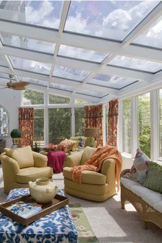 a living room filled with lots of furniture under a glass roof covered in windows and curtains