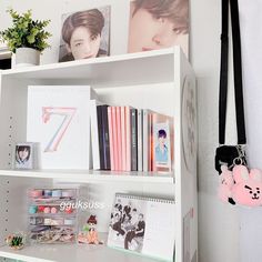 a white book shelf filled with lots of books next to a pink teddy bear keychain