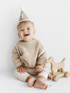 a baby sitting on the floor wearing a birthday hat