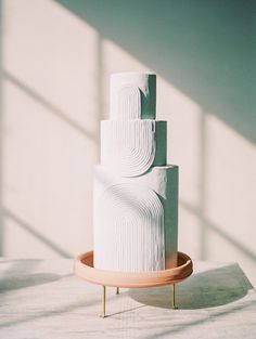 a three tiered white cake sitting on top of a wooden tray next to a window