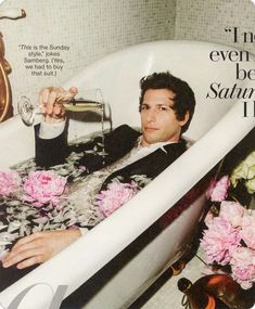 a man in a bathtub drinking from a wine glass with pink flowers on it