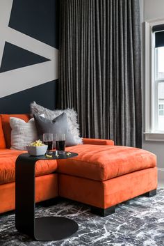 a living room with an orange couch and black table in front of the window,