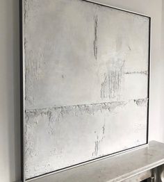 a large white painting on the wall above a fireplace