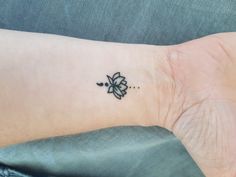 a small black flower tattoo on the wrist