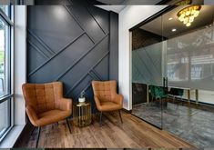 two brown chairs sitting next to each other on top of a hard wood floor in front of a window