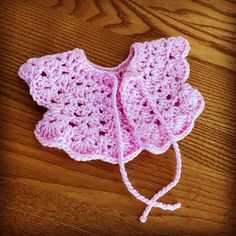 a pink crocheted hat sitting on top of a wooden table