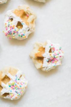 six donuts with white frosting and sprinkles are arranged on a table