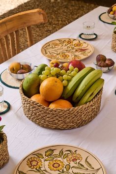 a table topped with plates and bowls filled with fruit sitting on top of a white table cloth