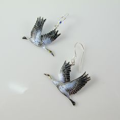 For lovers of Sandhill Cranes we offer this pair of fun yet fashionable earrings, crafted of sterling silver and adorned in cloisonné enamel. The Birds dangle from a French hook that has a Swarovski crystal attached for added interest and are lightweight and well detailed. Each earring is 1.25 inches in height from hook to belly and is 1 inch wide. They are new, in excellent condition, and marked 925 on the back although the enamel makes it hard to see. Be sure to take a peek at the matching bro Hand Painted Silver Dangle Jewelry, Hand Painted Sterling Silver Earrings For Gift, Hand Painted Sterling Silver Dangle Jewelry, Silver Enamel Earrings For Anniversary, Silver Painted Drop Earrings, Silver Hand Painted Drop Earrings, Silver Enamel Drop Earrings, Black Crane Clothing, Crane Earrings