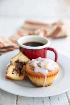 a white plate topped with cupcakes next to a red mug filled with coffee