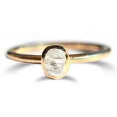 a gold ring with a white diamond on it's center and a thin band