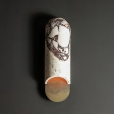 an object made out of marble on top of a black surface with a white and brown design