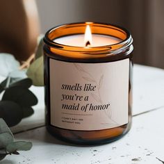 a candle sitting on top of a white table next to some flowers and leaves with a quote