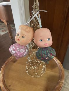 two little dolls sitting on top of a wooden table next to a chandelier