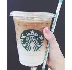 a hand holding a starbucks drink with a straw in it