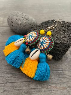 Unique fun and colorful earrings. Made with yellow and blue tassels and a beautiful round center piece made with different fabrics and strings, the earrings are adorned with beads, brass bells and shells. This pair will rock your outfit. Fun and easy to wear as they are super light. The earrings are 6cm- 2.40inch long 5.3cm- 2.10inch wide This timeless pair will brighten up your days! To see more unique and fun colorful tassel earrings, click the link below https://www.etsy.com/shop/AkashiJewelr Bohemian Green Tassel Earrings For Beach, Green Tassel Beach Earrings, Blue Tassel Drop Earrings For Festival, Bohemian Beaded Earrings With Latkans For Beach, Beach Earrings With Latkans, Bohemian Beaded Tassel Earrings For Beach, Beach Green Tassel Earrings, Blue Festival Earrings With Latkans, Blue Fringe Earrings For Festivals