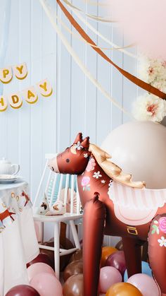 an image of a birthday party with balloons and horse statue on the floor in front of it