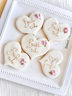 six decorated heart shaped cookies on a white platter with the words bride and groom written on them