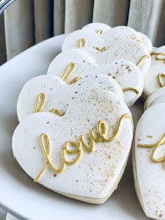 heart shaped cookies with the word love spelled in gold glitters on a white plate