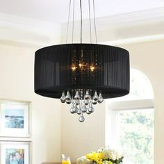 a black chandelier hangs over a dining room table with yellow flowers in the center