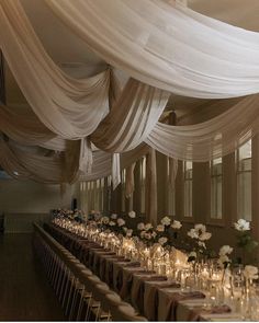 a banquet hall with tables covered in white draping and flower centerpieces