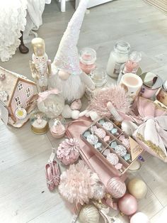 an assortment of pink and white items on the floor in front of a christmas tree