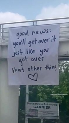 a sign hanging from the side of a building that says good news you'll get over it just like you got over that other thing