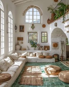 a living room filled with lots of white furniture and plants on top of it's walls