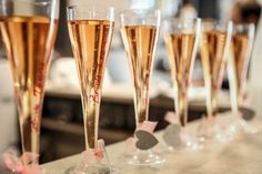 five champagne flutes are lined up on a bar with pink bows and hearts in them