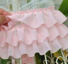 a hand is holding a pink ruffled skirt