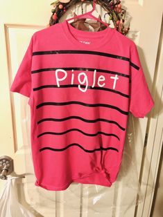 a pink shirt with the word piglet on it hanging from a door hanger