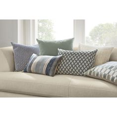 a couch with several pillows on it in front of a window and some windowsills