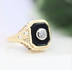 Beautifully-detailed gold onyx diamond ring. Chunky Old European Cut diamond bezel set in 18k white gold. The rest of the ring is fashioned from 14k gold. Fabulous filigree gallery and shoulders. The ring is a warm white gold. Meaning, I believe it is white gold alloy that has yellowed over time. It could also be a purposeful very light yellow gold. Size 3.75 - 4 *Diamond: 2.7mm 0.07ct SI1-I2 G-H Onyx: 7.24 mm x 5.64 mm Weight: 2.1g Very good antique condition. No breaks in the filigree. Stones Elegant Black Ring With Single Diamond, Art Deco 14k Gold Jewelry With Center Stone, Exquisite Bezel Set Jewelry For Anniversary, Exquisite Jewelry With Bezel Setting For Anniversary, Exquisite Diamond Rings With Bezel Setting, Art Deco Bezel Set Ring, Black Diamond Rings With Bezel Setting, Classic Black Ring With Single Diamond, Black Ring With Single Diamond In Fine Jewelry Style