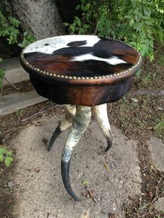 an animal print stool sitting on top of a cement ground next to a tree and bushes