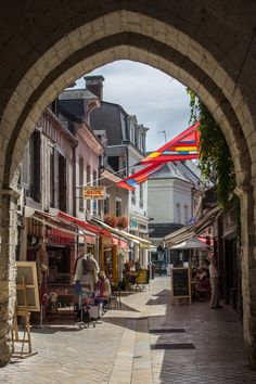 an archway in the middle of a street with people walking and shops on both sides