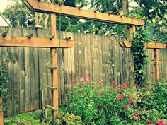 a wooden fence surrounded by flowers and plants