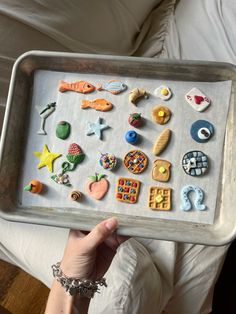 a person holding a tray full of different types of cookies and pastries on it