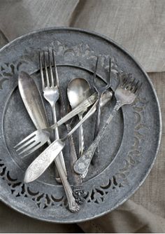 there is a plate with silverware on it that has spoons, forks and knives in it