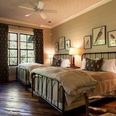 two beds in a room with wooden floors and pictures hanging on the wall above them