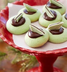 green cookies with chocolate on top are sitting on a red platter, ready to be eaten