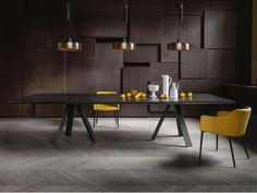 a dining room table with yellow chairs in front of dark wood paneled walls and flooring