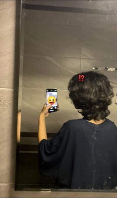 a person taking a selfie in front of a mirror with an emoticive smiley face on it