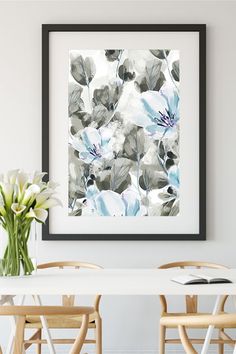 a white table with some chairs and a vase on top of it next to a painting