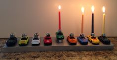 there are many toy cars lined up on the table with candles in front of them