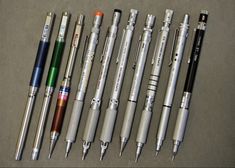 several pens are lined up next to each other on a table with one pen in the middle