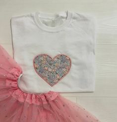 a white shirt with a heart on it and pink tutule next to it