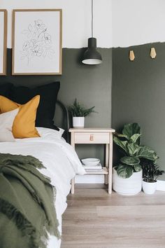 a bed room with a neatly made bed and two plants on the nightstands next to it