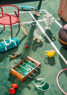 an assortment of sports equipment and toys on a green carpeted floor, including a foosball table