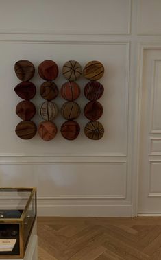 a display case with basketballs on it in a white walled room next to a wooden floor